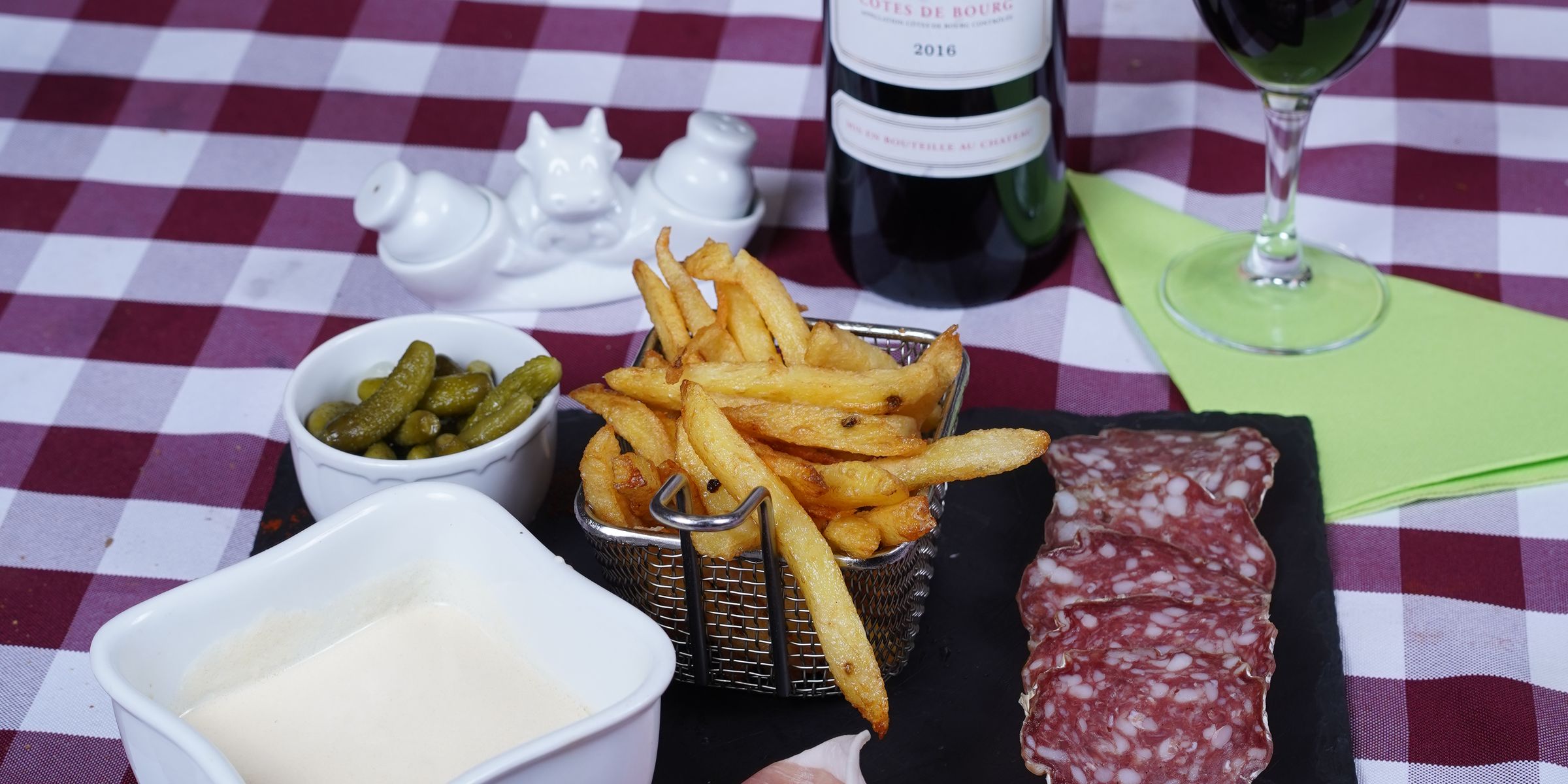 Du fromage fondu, des frites, de la charcuterie et des cornichons sur une ardoise