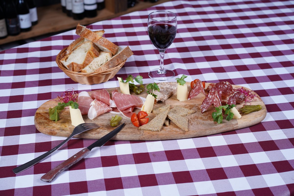 Une planche de charcuterie du restaurant, avec du pain de campagne et un verre de vin rouge