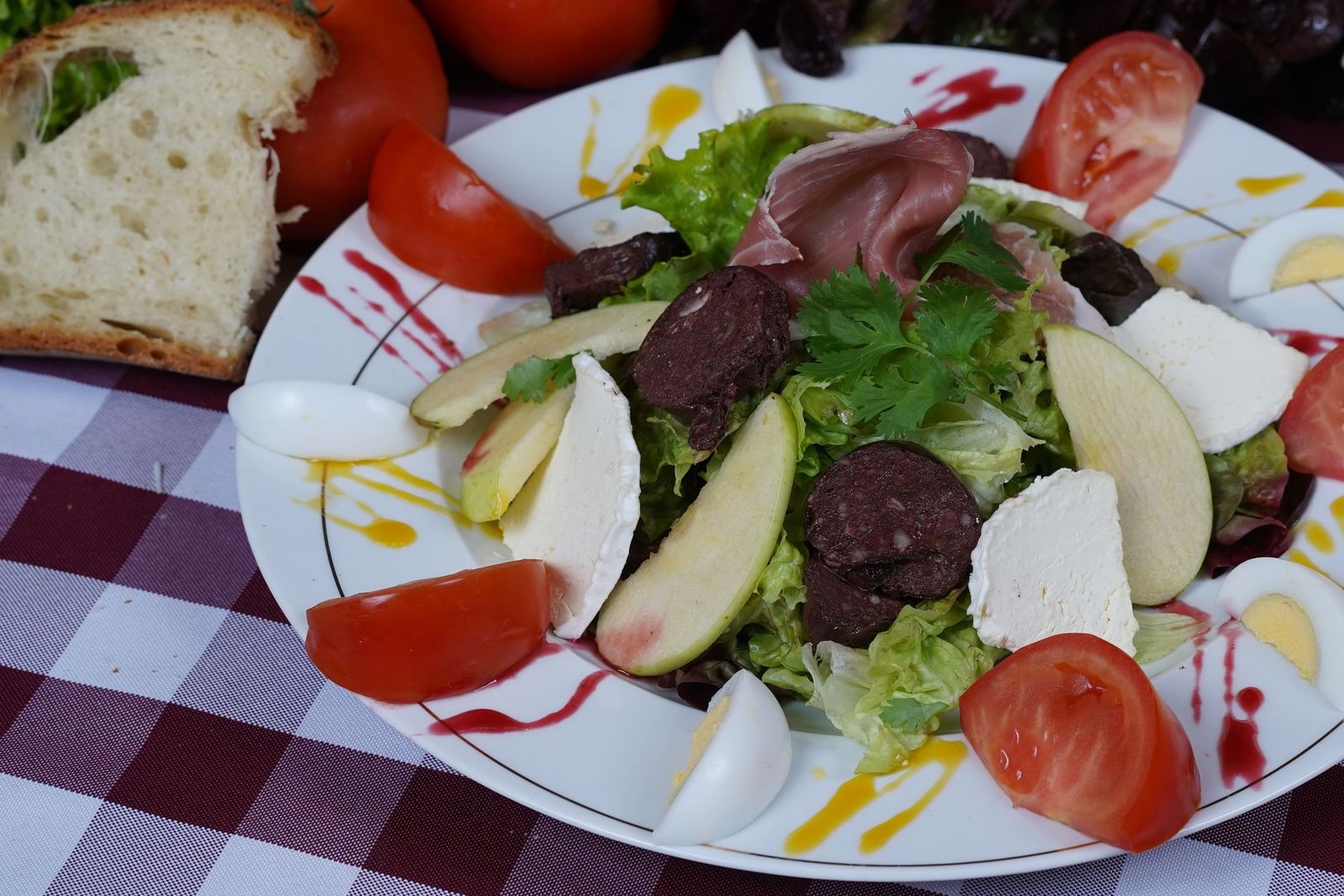 Une grande salade composée : jambon de pays, boudin noir, pomme, fromage frais, œufs durs et tomates