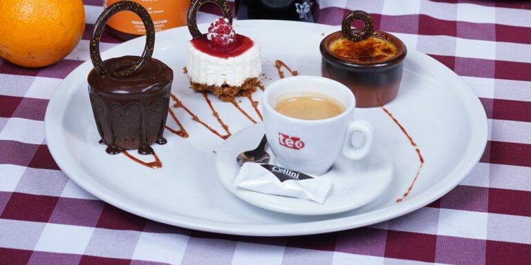 Un café gourmand du restaurant : un expresso entouré de trois petits desserts, sur une assiette blanche